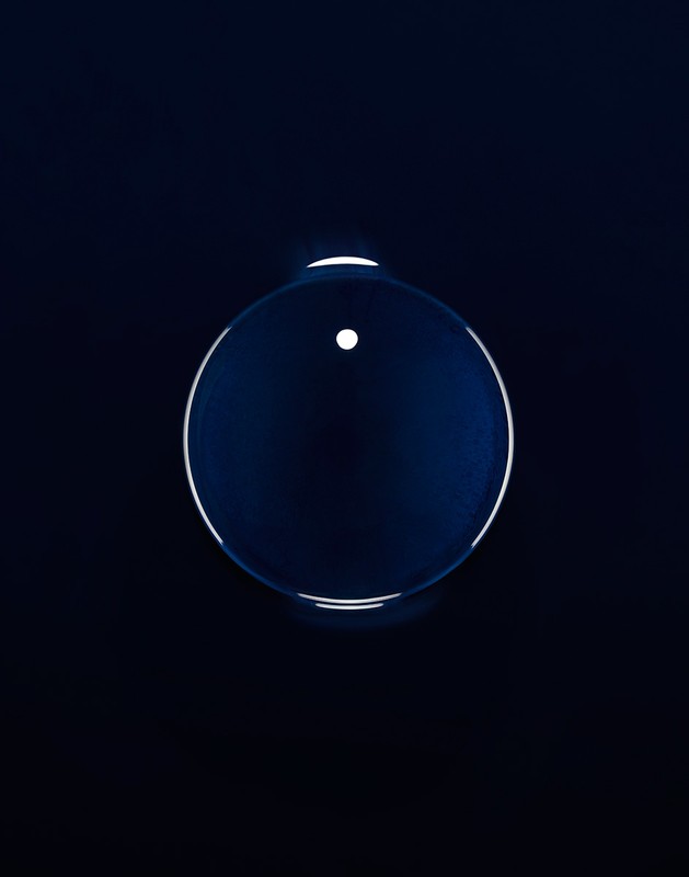 Abstract shot of a translucent sphere against a dark background. The sphere has a white dot and a bright outline.