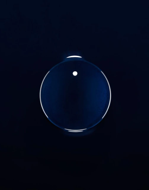 Abstract shot of a translucent sphere against a dark background. The sphere has a white dot and a bright outline.
