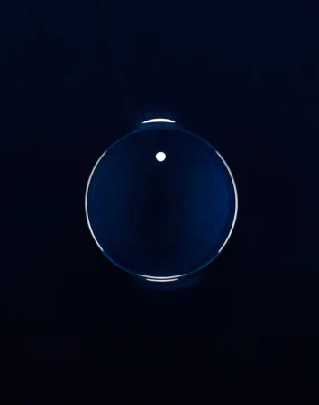 Abstract shot of a translucent sphere against a dark background. The sphere has a white dot and a bright outline.
