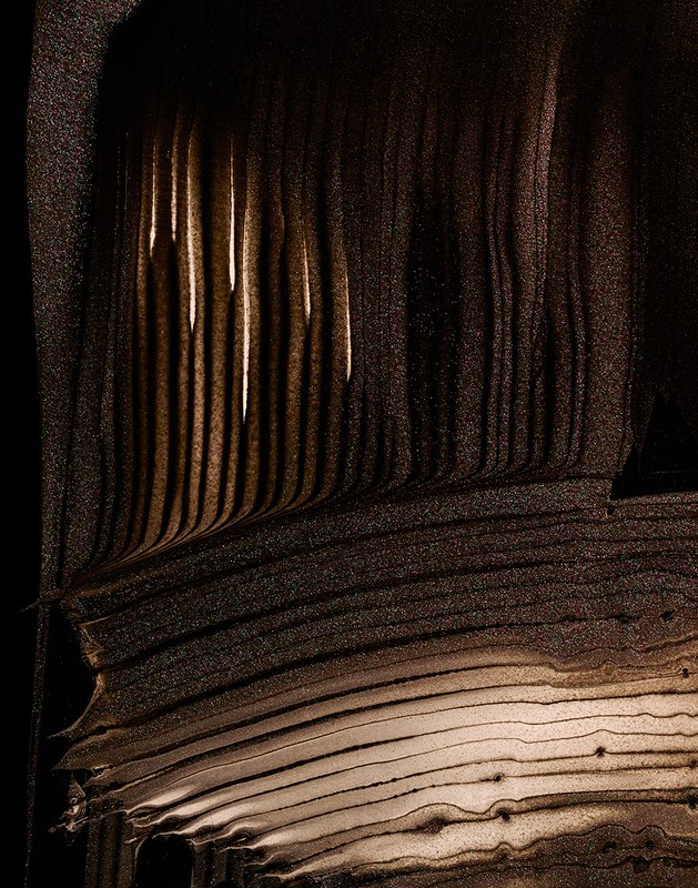 Abstract textured image with vertical and horizontal lines in shades of brown and black, resembling a geological formation.