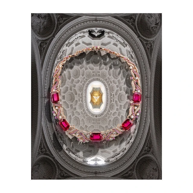 Elegant gold necklace with pink gemstones on a patterned ceiling backdrop, set against a white background for jewelry presentation.