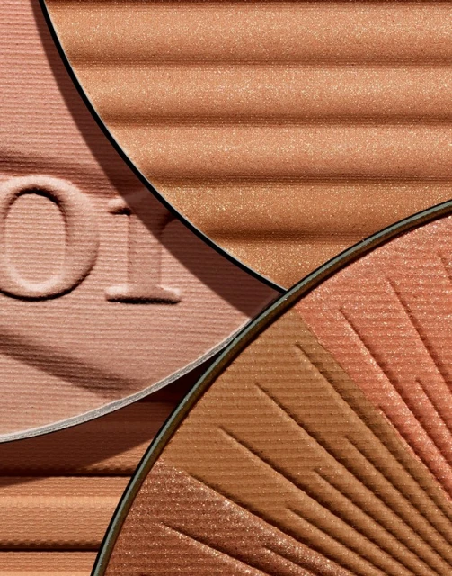 Close-up of pressed powder makeup in peach, bronze, and brown tones with a ribbed and fan pattern.