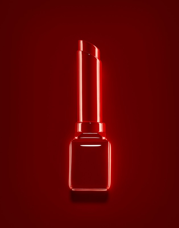 Close-up of a shiny red lipstick tube on a dark red background, product shot. Beauty, fashion, and cosmetic industry aesthetic.