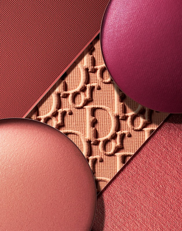 Overhead studio shot showcasing blush makeup products, featuring circular blush compacts and embossed logo pattern in terracotta hues.