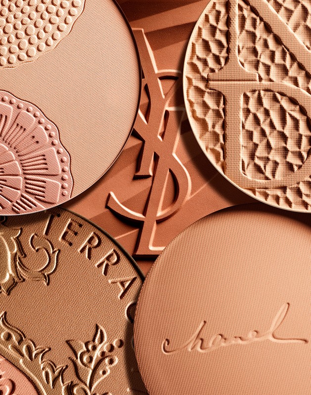 Macro shot of luxury cosmetic compacts featuring embossed brand logos and intricate designs, showcasing high-end beauty and texture.