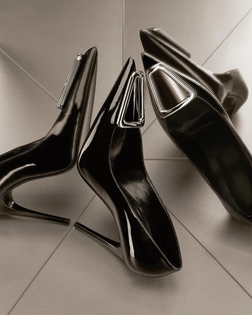 Studio shot of three black patent leather high heel shoes with silver hardware accents on a glossy tile surface, fashion forward footwear.