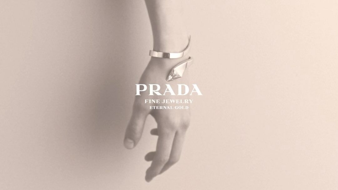 Close-up of a human wrist and hand wearing a sleek silver cuff bracelet against a soft neutral background.