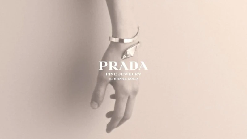 Close-up of a human wrist and hand wearing a sleek silver cuff bracelet against a soft neutral background.