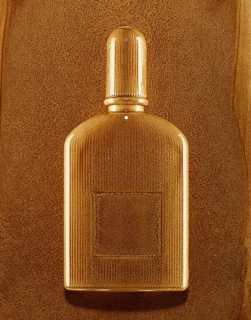 A gold ribbed perfume bottle with a matching cap photographed against a textured golden brown background by Coppi Barbieri