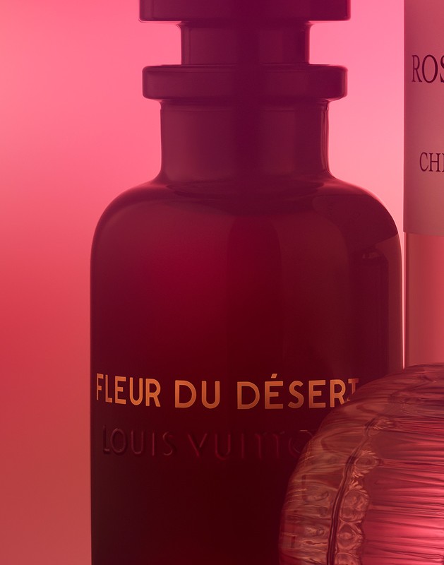 Close-up studio shot of Louis Vuitton Fleur du Désert fragrance bottle, displaying luxurious packaging and rich color gradients.