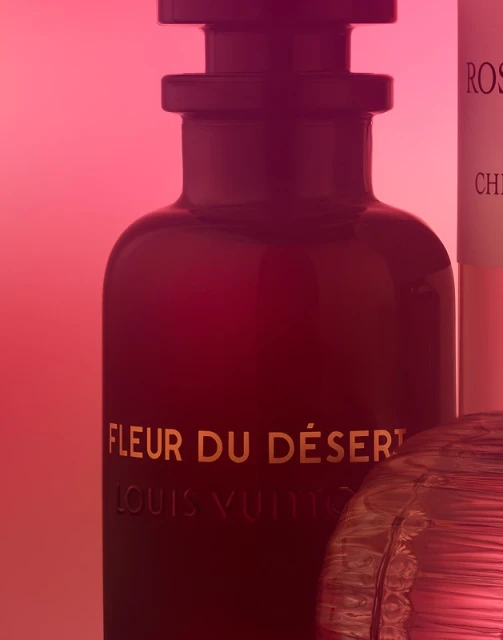 Close-up studio shot of Louis Vuitton Fleur du Désert fragrance bottle, displaying luxurious packaging and rich color gradients.