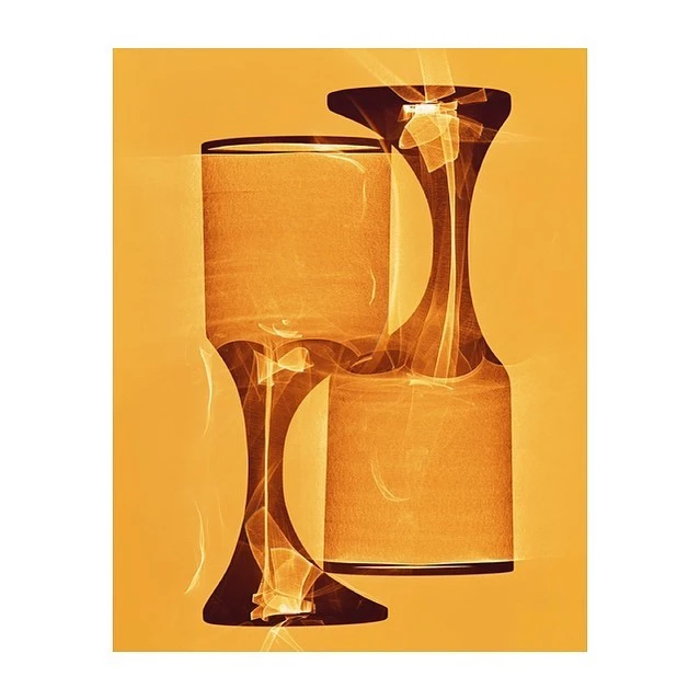 Abstract image of two glass objects in shades of orange and brown, set against a vibrant orange background, creating a surreal design.
