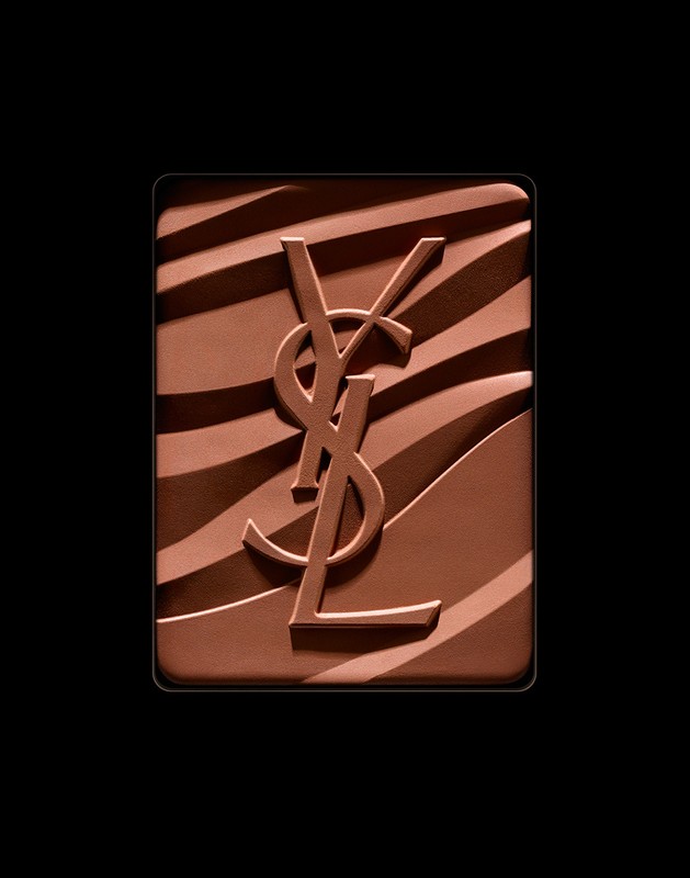 Close-up of YSL bronzer powder with signature logo embossed on a brown and tan zebra stripe pattern against a solid black backdrop.