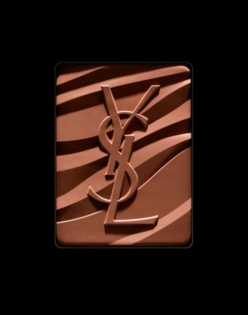 Close-up of YSL bronzer powder with signature logo embossed on a brown and tan zebra stripe pattern against a solid black backdrop.