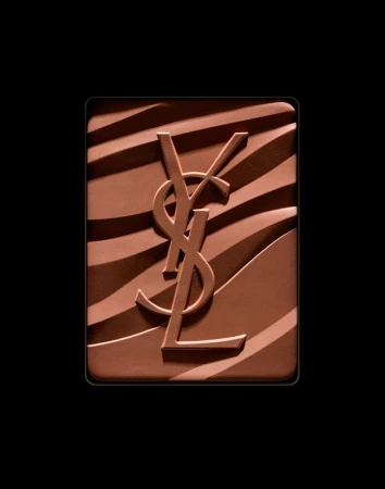 Close-up of YSL bronzer powder with signature logo embossed on a brown and tan zebra stripe pattern against a solid black backdrop.