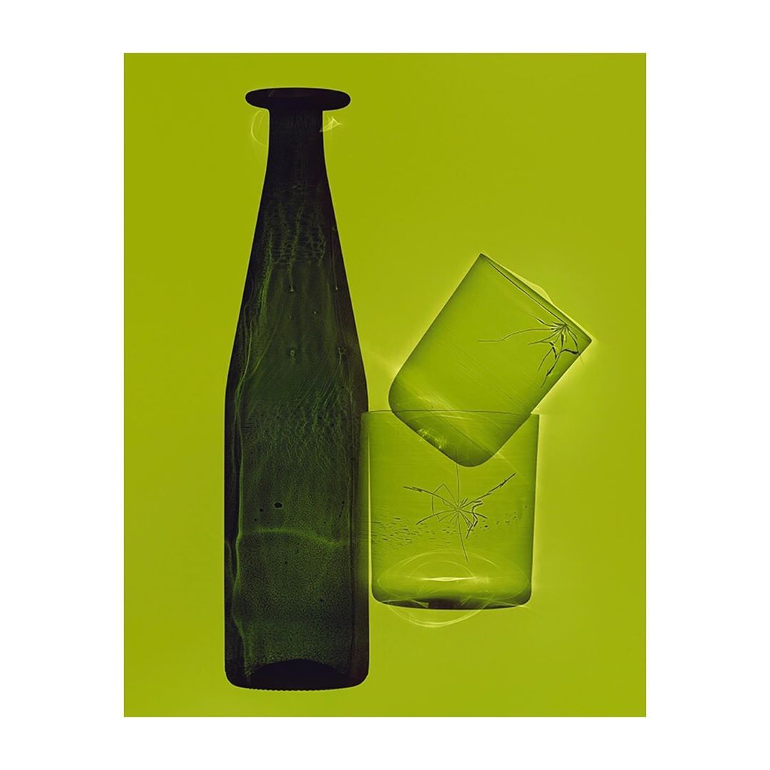 Still life featuring a green glass bottle and two stacked cracked glasses against a bright green background, creating a minimalist composition.