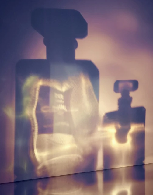 Shadows of perfume bottles on a wall create an elegant, minimalist composition with a focus on light and form, creating a visually striking effect.