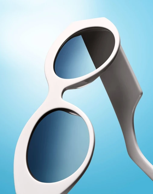 Stylish white-rimmed sunglasses with blue gradient lenses on a gradient blue background in a product photography style shot.