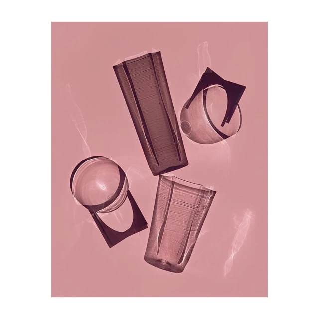 Still life shot of transparent drinking glasses in varying shapes and sizes, arranged against a pink backdrop with lens flares.