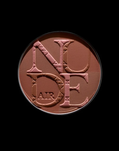 Close-up of Dior Nude Air Tan powder compact. The bronzer palette features raised lettering. Earthy tones dominate the cosmetic product.