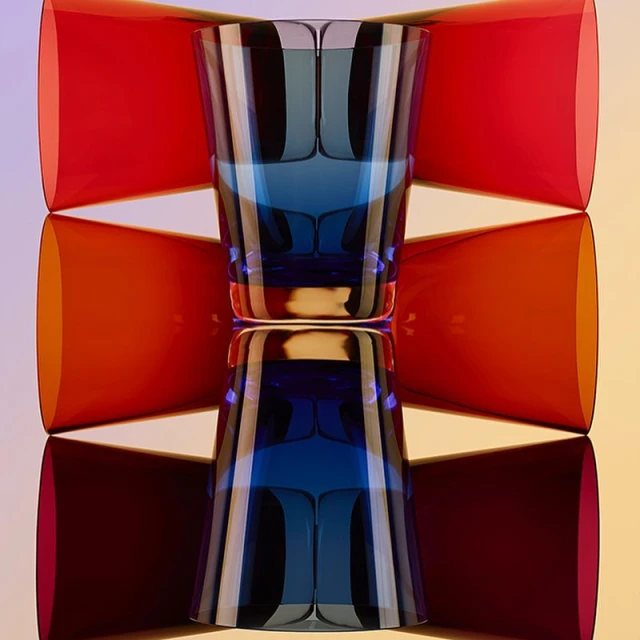 Art photography of a blue glass reflected on a surface, framed by red and orange geometric shapes, creating a symmetrical, colourful composition.