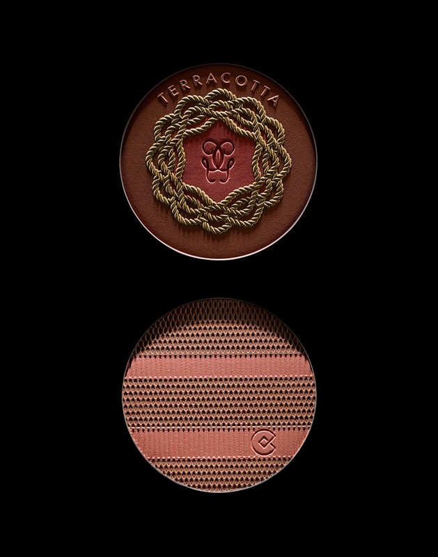 Close-up of terracotta bronzing powder compacts from Guerlain. The top features a rope wreath and the bottom has a geometric pattern.