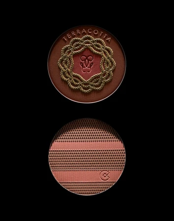 Close-up of terracotta bronzing powder compacts from Guerlain. The top features a rope wreath and the bottom has a geometric pattern.