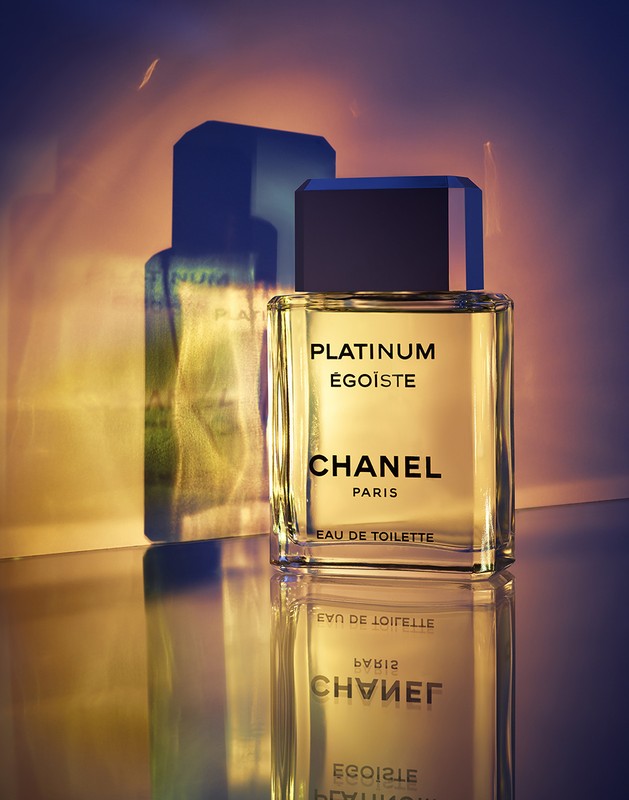Chanel Platinum Égoïste Eau de Toilette bottle stands on a reflective surface with its shadow cast on a gradient background.