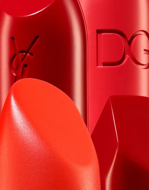Close-up studio shot of two bright red lipsticks with embossed luxury brand logos, showcasing makeup, beauty, and cosmetic product details.