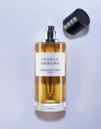 Christian Dior Vanilla Diorama perfume bottle upright with its cylindrical black cap resting beside it.