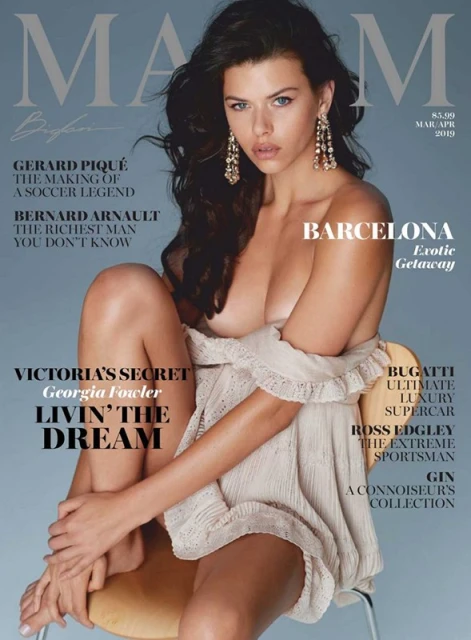 Magazine cover featuring an adult female with long dark hair, wearing a light-colored dress, seated on a chair against a light blue background.