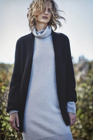 Model with tousled blonde hair wearing a grey turtleneck dress and black cardigan outdoors in Los Angeles