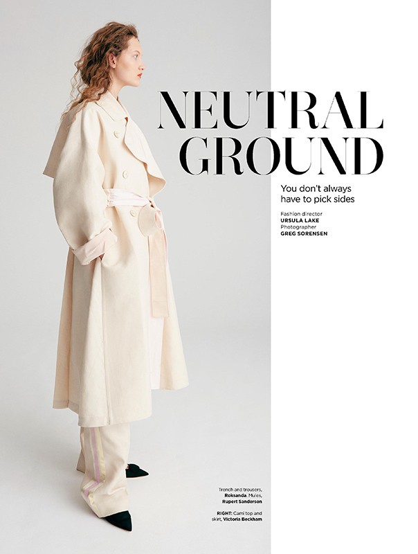 Model wearing a long cream trench coat and matching trousers standing against a plain white studio background.