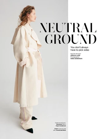 Model wearing a long cream trench coat and matching trousers standing against a plain white studio background.