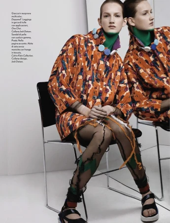 Two female models in patterned coats and sandals sitting on chairs with makeup by Cynthia Sobek