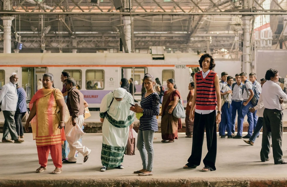 Candid shot of people waiting on a train platform, with a train in the background, showcasing everyday life and travel.