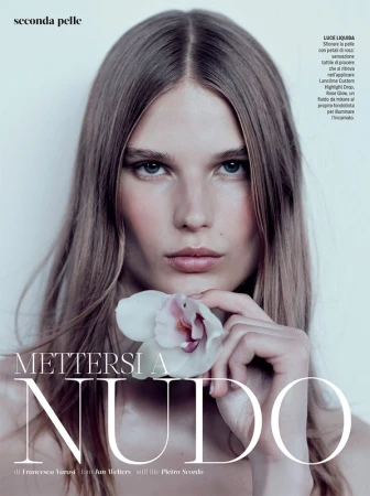 Beauty shot of a young adult woman with long blonde hair holding a white orchid flower, studio lighting, fashion editorial.