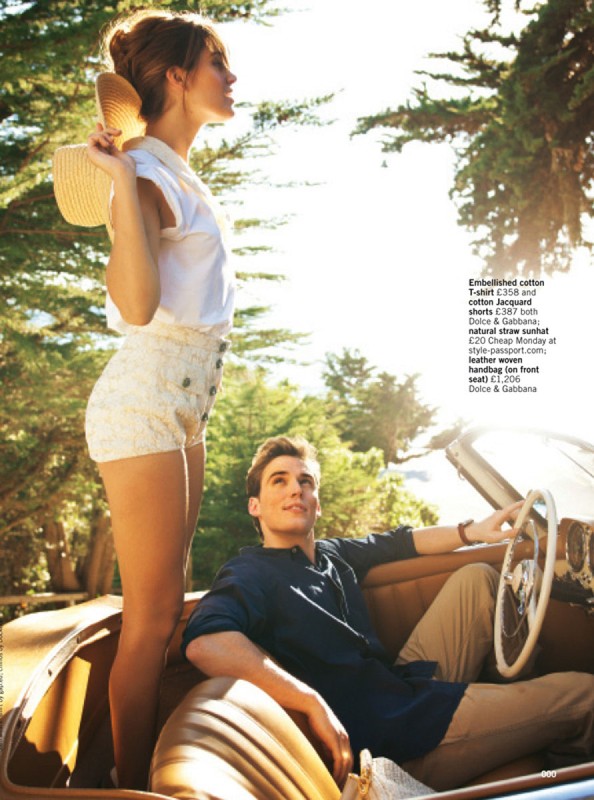 A fashionable couple poses in a vintage convertible car on a sunny day near trees, showcasing summer apparel and accessories.