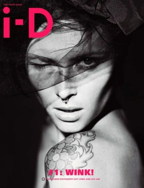 Black and white magazine cover shot featuring a winking adult female with a floral tattoo and black veil. I-D magazine logo in pink.