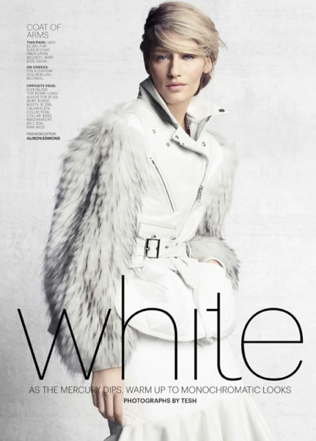 Editorial fashion shot of a model wearing a white leather jacket with fur trim and a short blonde hairstyle against a white backdrop.