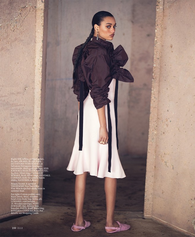 Fashion editorial shot of a Black female model wearing a brown top and white dress, posing in a concrete doorway.