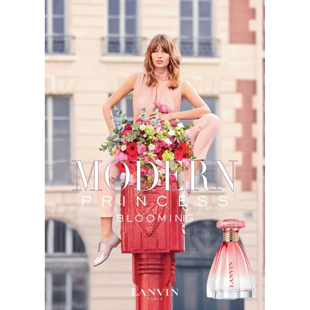 Fashion photography features a woman in light pink attire atop a red pillar, surrounded by flowers, advertising Lanvin perfume against a building backdrop.