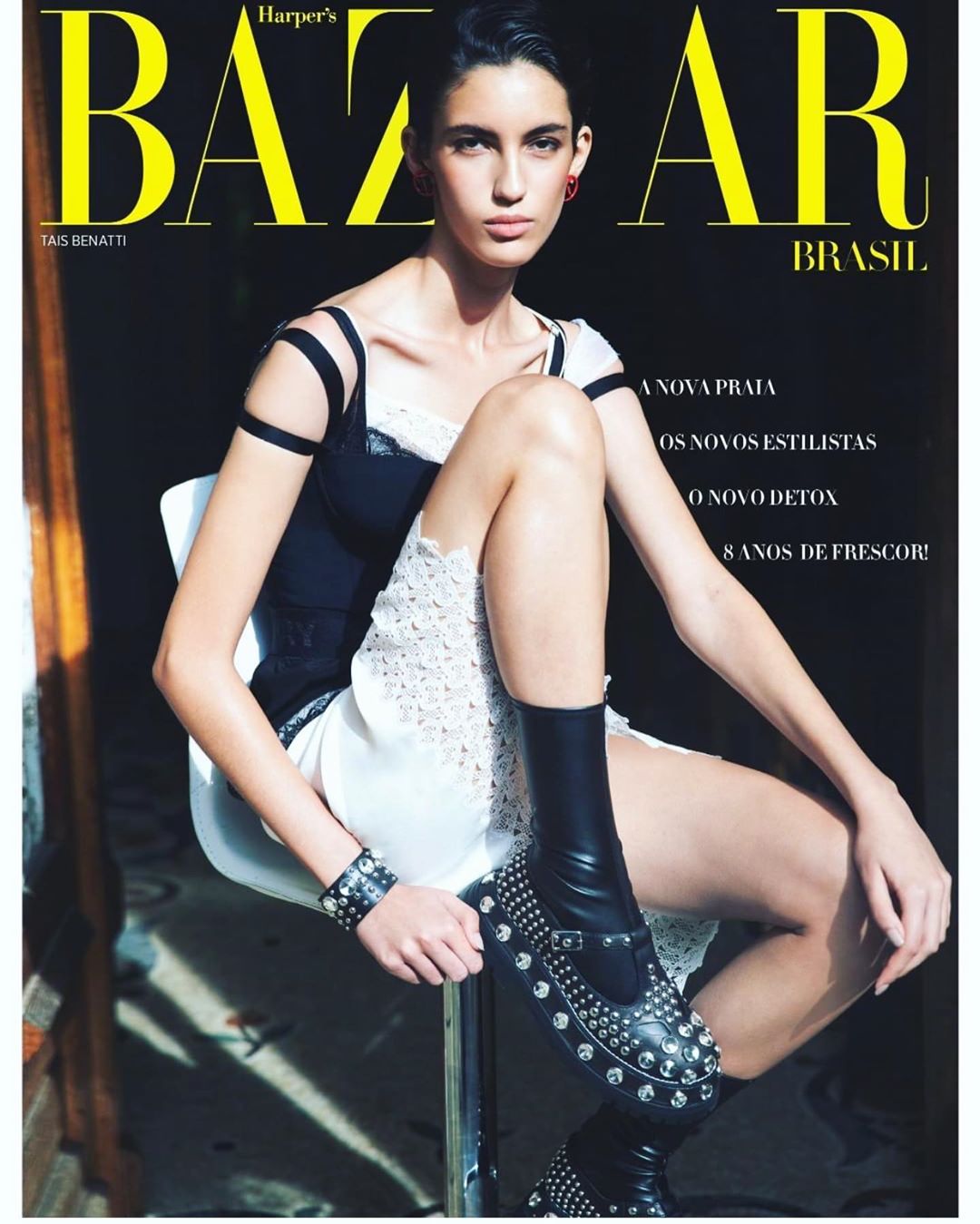 Magazine cover featuring a model in black and white fashion sitting on a stool. The cover is for Harper's Bazaar Brasil.
