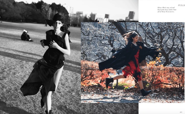 Black and white fashion editorial shot of a woman in avant-garde black clothing running in a grassy field with cityscape background.