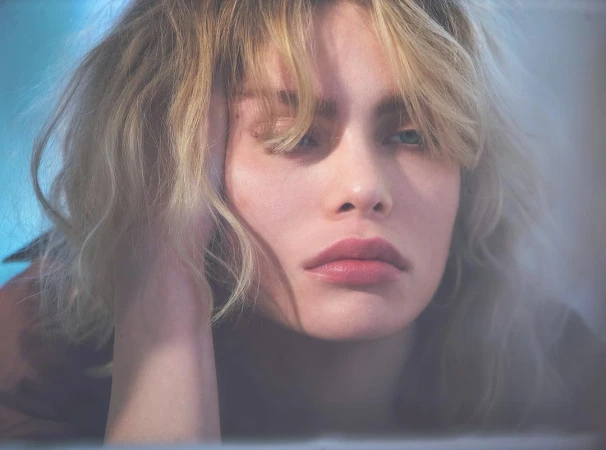 Close up portrait of a blonde woman resting her head on her hand with soft natural lighting and a thoughtful expression