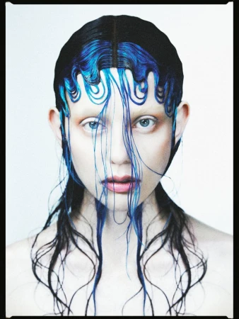 Striking close-up of a fashion model with creative black and blue hair, showcasing edgy beauty and avant-garde style in a studio setting.