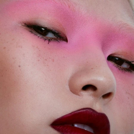 Close up beauty portrait of a person with vivid pink eyeshadow and deep burgundy lips by makeup artist David Razzano