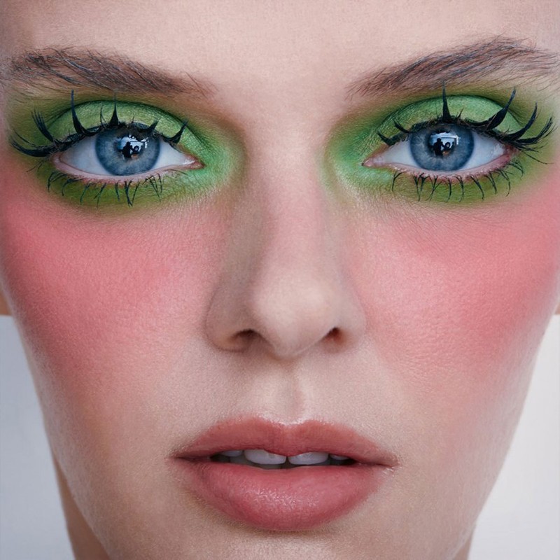 Close-up beauty portrait of a woman with vibrant green eyeshadow, dramatic black mascara, and soft pink blush by David Razzano