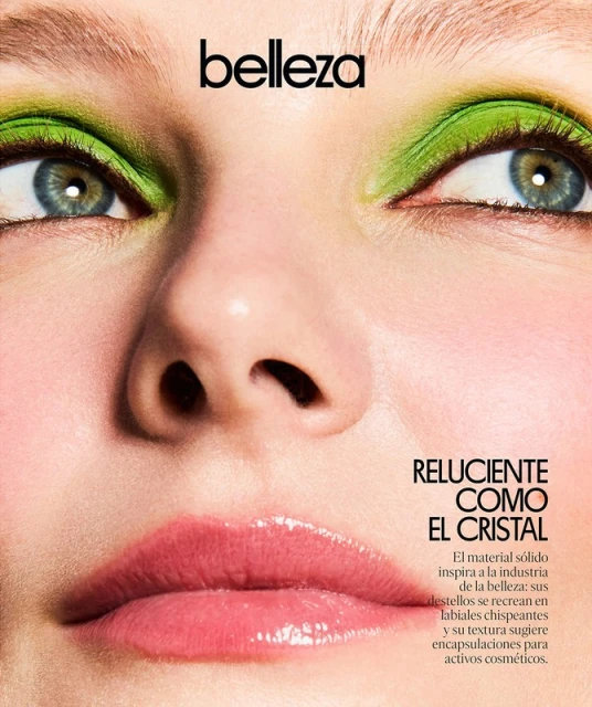 Close-up studio shot of a woman's face with vivid green eyeshadow, glossy pink lips, fair skin, and the word 'belleza' above her.
