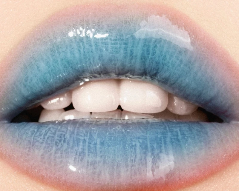 Macro close-up of bright blue glossy lips with white teeth showing, light skin. Beauty shot focused on unique lip color and texture.